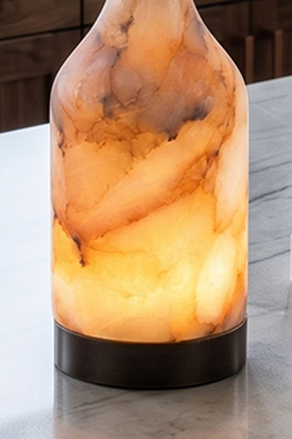 Evander Alabaster Bottle Table Lamp | Alabaster, Metal | Close-up shot highlighting the organic clouds, translucent stone body, and dark metal base on a polished kitchen countertop | Detail shot | vexa lamps