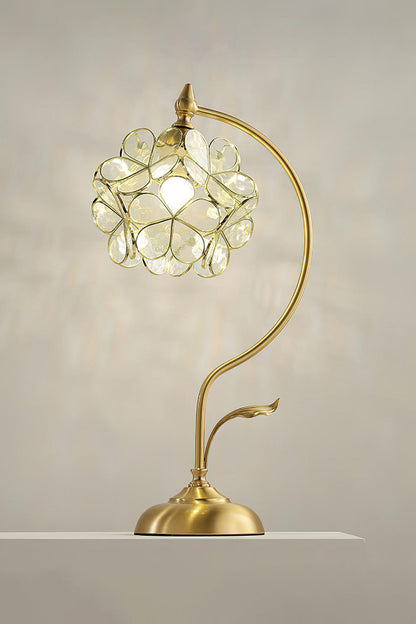 Evanthe Blossom Stained Glass Table Lamp | Stained Glass, Metal | Fully illuminated warm cream white variant casting a brilliant textured shadow halo on a grey studio wall | vexa lamps