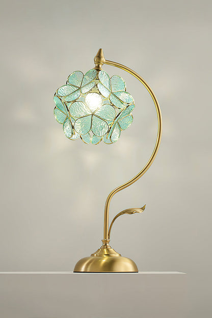 Evanthe Blossom Stained Glass Table Lamp | Stained Glass, Metal | Studio view of the mint green glass variant fully lit, projecting a soft botanical backlight halo on a plain neutral wall | vexa lamps
