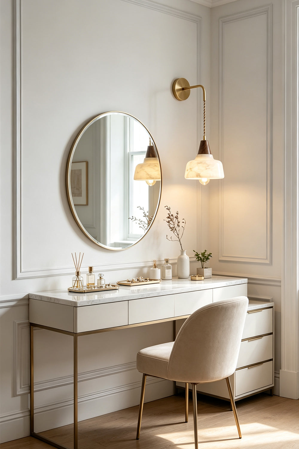 Everett Alabaster Hook-Arm Wall Sconce illuminating a chic vanity with mirror and decor.