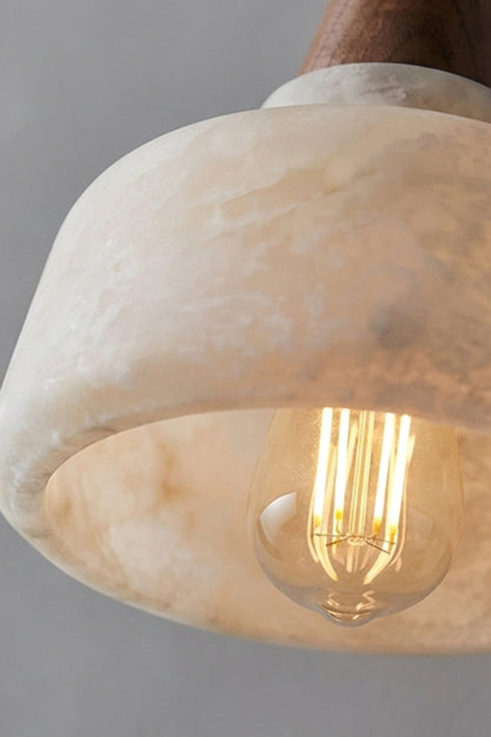 Close-up of the flared shade of the Everett Alabaster Hook-Arm Wall Sconce highlighting its natural alabaster texture.
