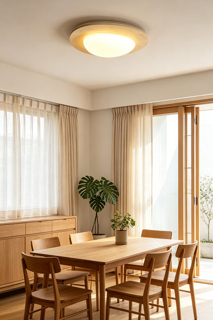 Geoidal Halo Travertine Ceiling Light | Travertine, Glass | Lit over a wooden dining table with chairs and potted plants | vexa lamps
