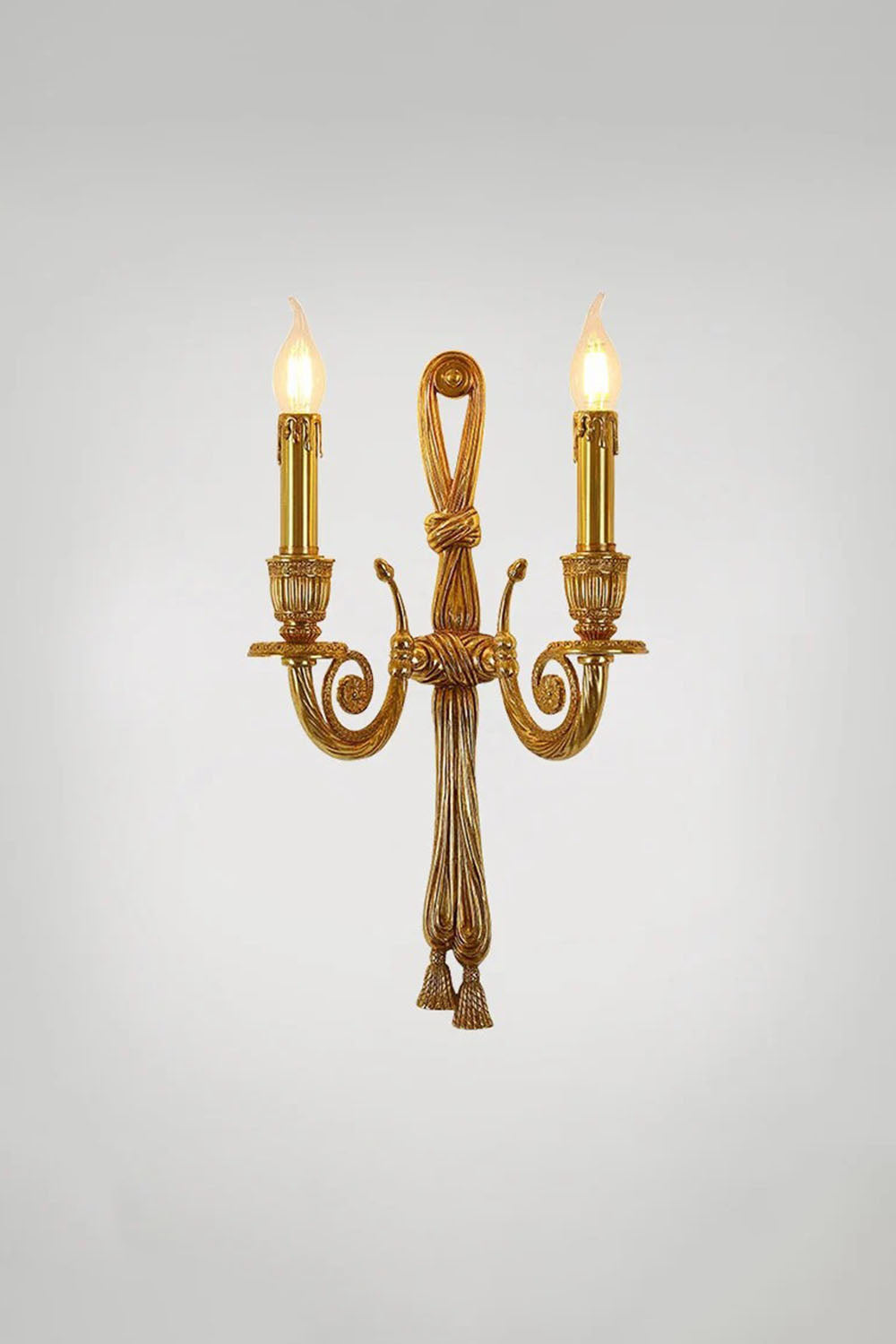 Honoria Rope and Tassel Brass Sconce | Brass and Metal | Studio shot showing the full sconce glowing warmly against a grey backdrop | vexa lamps