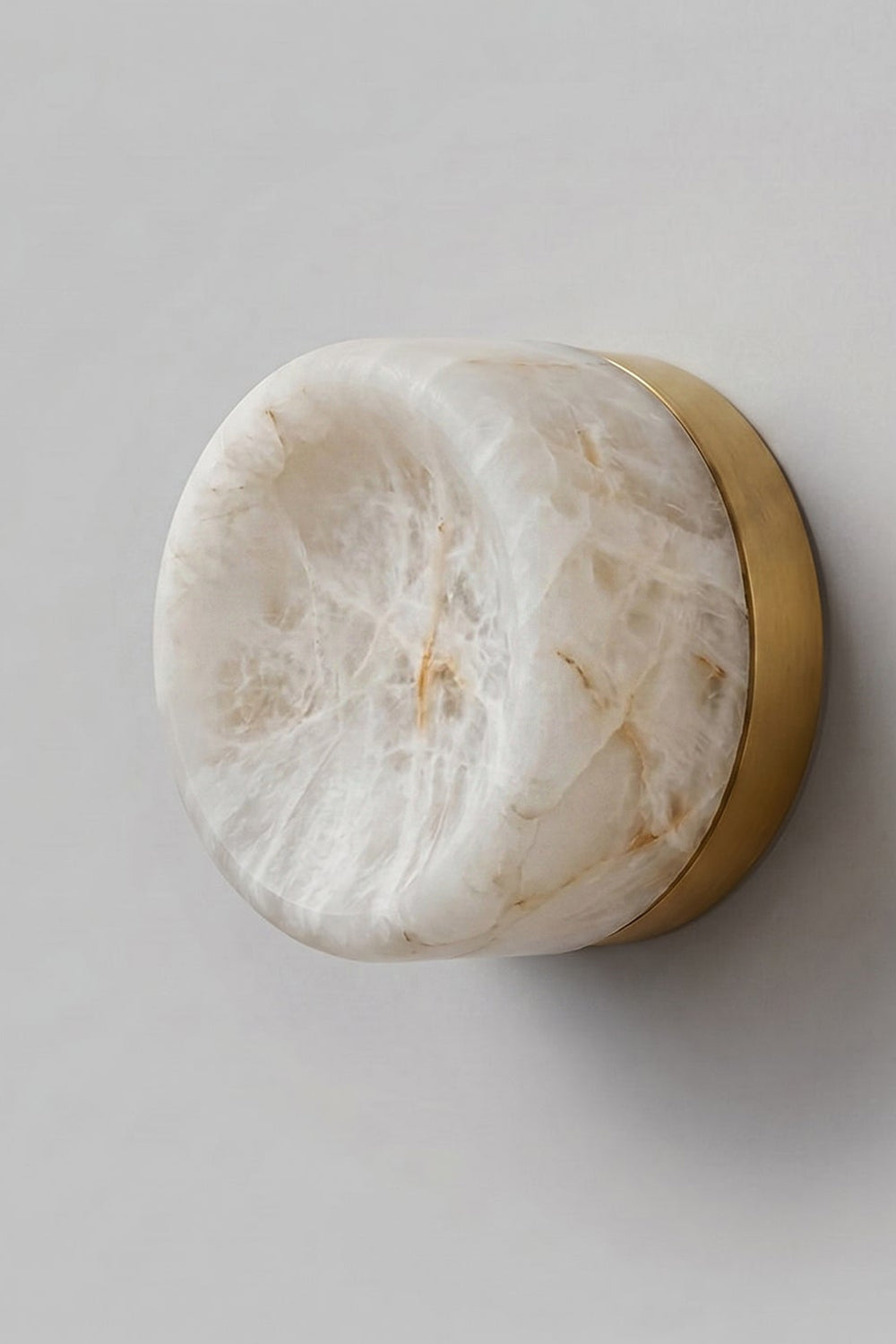 Isolde Concave Alabaster Disc Wall Sconce | Natural Alabaster and Brass | Studio close-up shot showing the natural stone veins and brass backplate on a light wall | vexa lamps