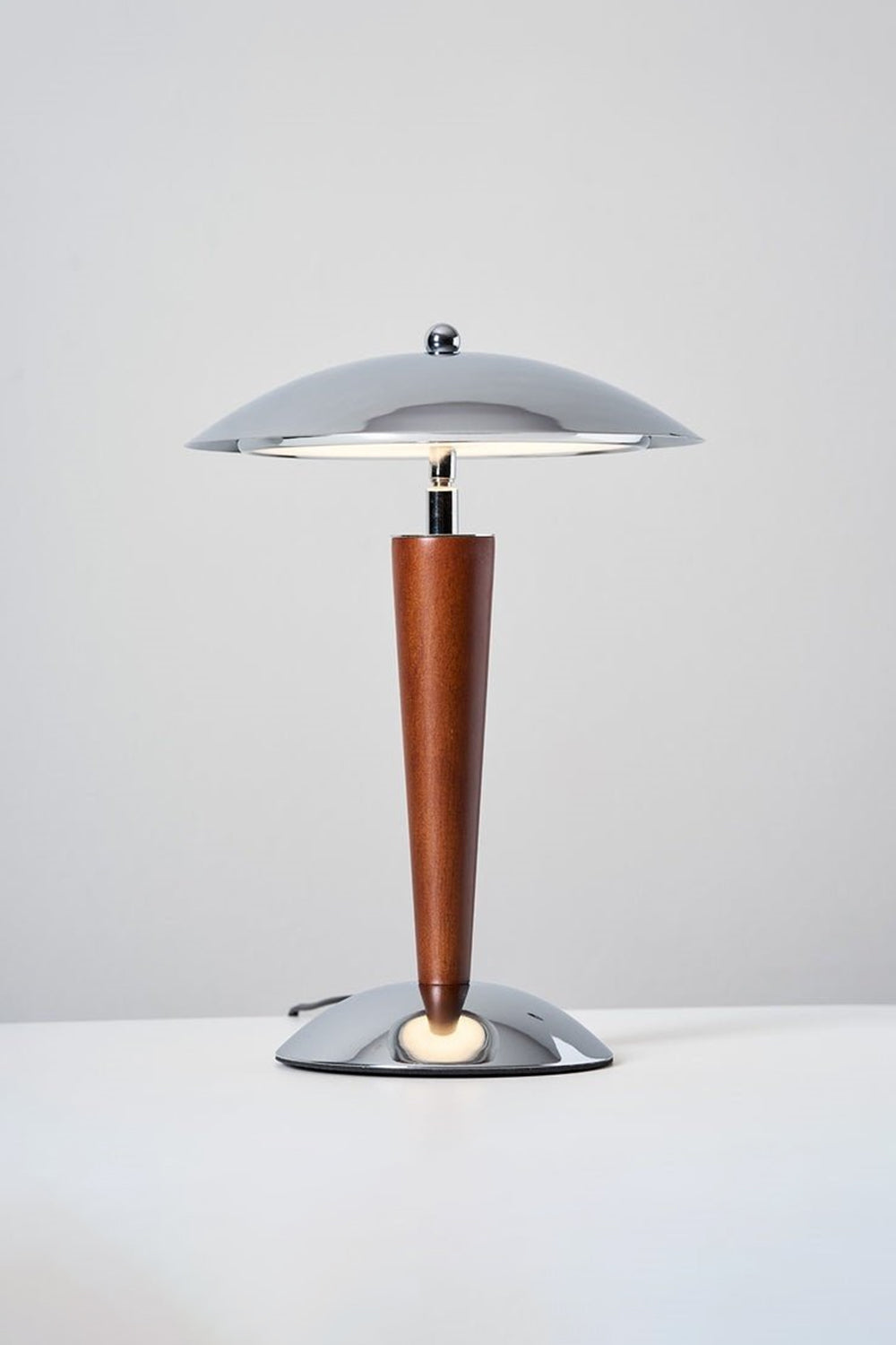 Isolde Domed Walnut Table Lamp | Illuminated Neck Detail | Close-up view underneath the lit dome shade showcasing the reflection on the chrome hardware and the top wood finish | Detail shot | vexa lamps