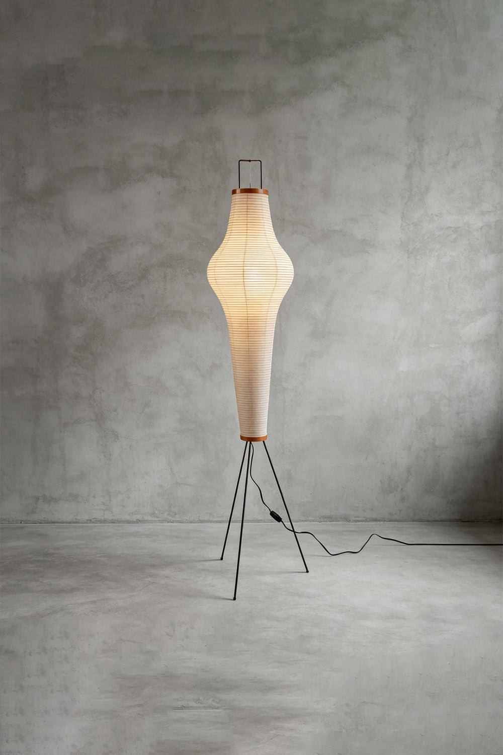 Isolde Ribbed Paper Column Floor Lamp standing on a slim metal frame, glowing softly from within, perfect for cozy spaces.