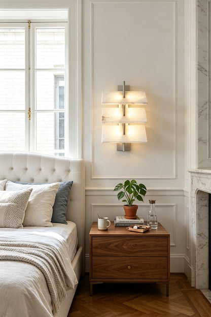 Isolde Tiered Alabaster Slab Wall Sconce illuminating a stylish bedroom beside a wooden nightstand.