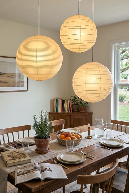 Komorebi Mulberry Paper Pendant Light | Paper, Bamboo | A trio of spherical paper lantern pendants casting a warm glow over a rustic wooden dining table decorated for a meal | vexa lamps