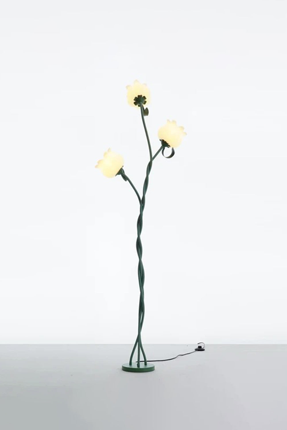 Linnea Tulip Bloom Floor Lamp | Glass and Green Metal | Full standing view glowing softly in a studio setting against a plain wall | vexa lamps