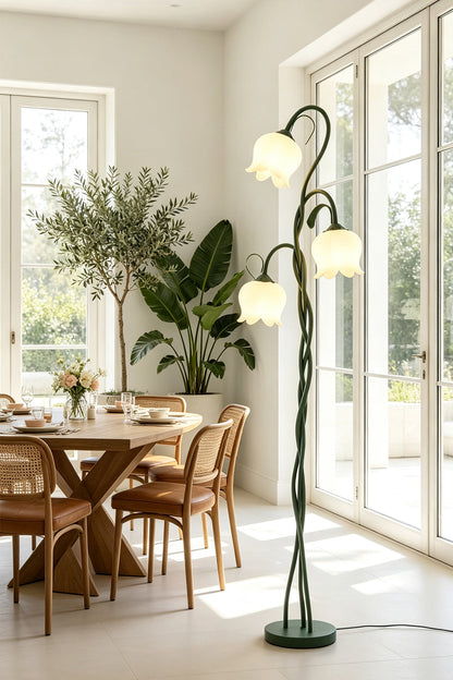 Linnea Tulip Bloom Floor Lamp | Glass and Green Metal | Illuminating a dining area featuring wooden furniture and large indoor plants | vexa lamps