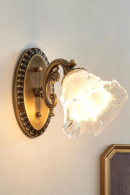 Lisette Blossom Glass Brass Wall Lamp | Glass and Brass | Side angled illuminated view glowing warmly against a plain wall | vexa lamps