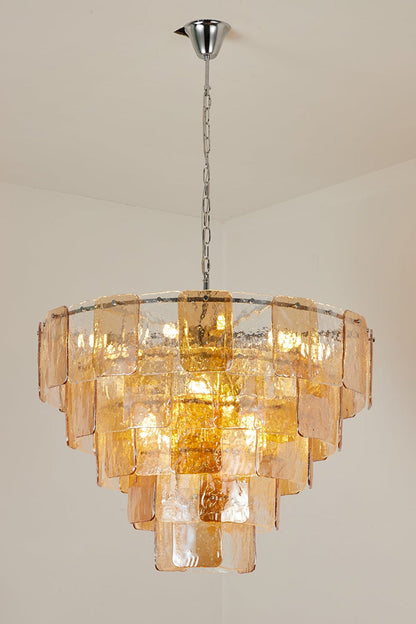 Lucia Tiered Amber Glass Chandelier | Glass, Metal | Alternative full studio shot of the illuminated tiered glass light fixture hanging elegantly against a grey studio backdrop | vexa lamps