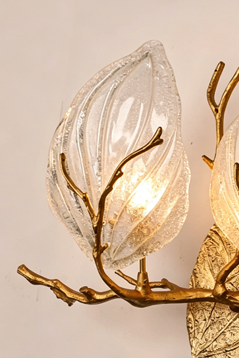 Magnolia Arbor Brass Wall Lamp | Brass, Glass | Close-up focus on the illuminated leaf-shaped clear glass shade and lifelike golden twig | Detail shot | vexa lamps