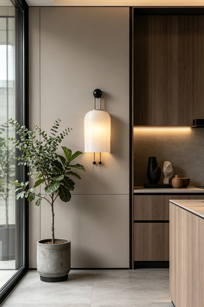 Marlow Linear Ribbed Glass Wall Lamp | Glass, Metal | Wall-mounted in a minimalist room transition corner near modern dark wood kitchen cabinetry and a potted tree | vexa lamps
