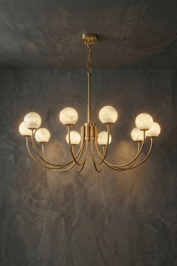 Lit 10-light brass chandelier | Alabaster, Brass | Slightly angled view against a concrete-style background | vexa lamps