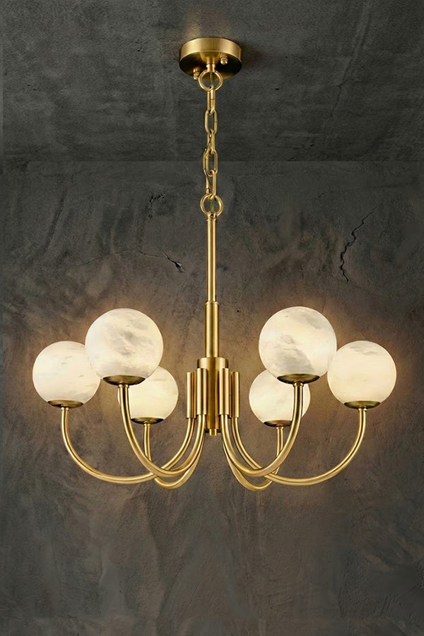 Lit 6-light brass chandelier | Alabaster, Brass | Slightly angled view against a concrete-style background | vexa lamps