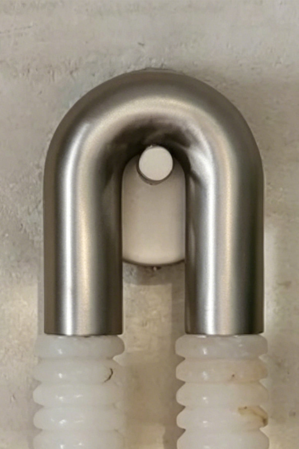 Monolith Arc Alabaster Wall Lamp | Alabaster, Metal | Close-up focus on the brushed metal U-arc and minimalist mounting point | Detail shot | vexa lamps