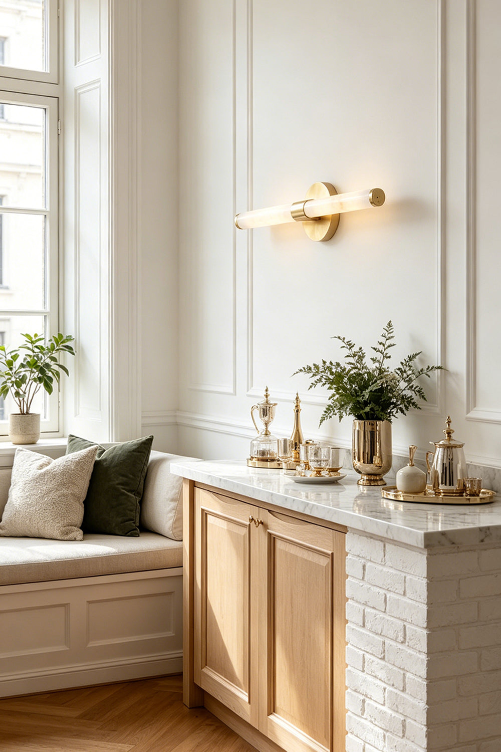 Nerida Linear Alabaster Wall Sconce | Alabaster, Brass | Positioned elegantly on a white paneled wall above a classic wooden sideboard cabinet with a marble top in a sunlit hallway lounge | vexa lamps