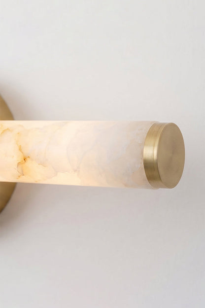 Nerida Linear Alabaster Wall Sconce | Alabaster, Brass | Detailed shot of the illuminated end of the alabaster tube showcasing a translucent soft warm glow and the matching gold brass cap | Detail shot | vexa lamps