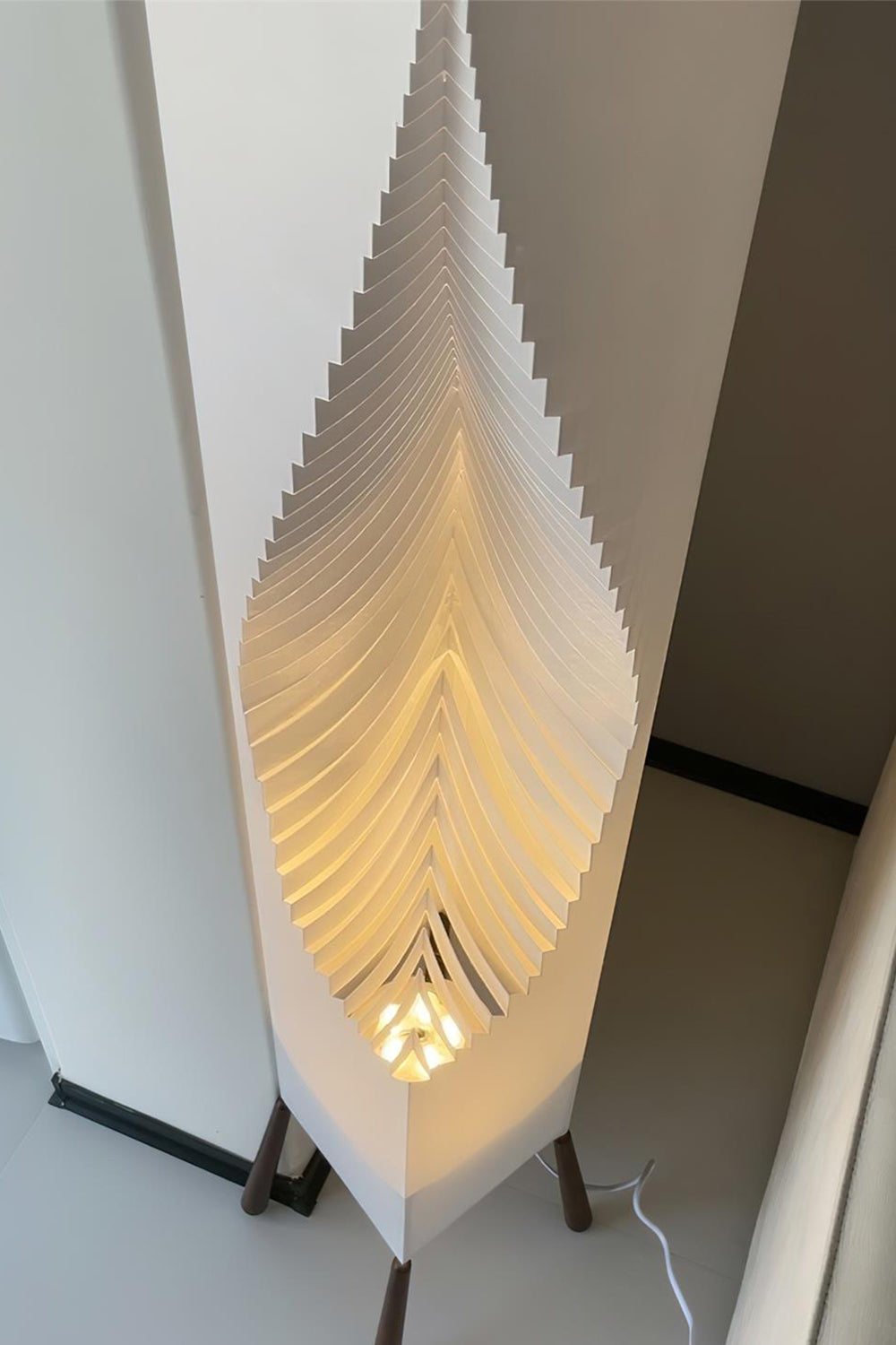 Nori Sculptural Leaf Floor Lamp | Fabric, Wood | Close-up side profile view of the glowing ribbed geometric folds of the sculptural white fabric shade | Detail shot | vexa lamps