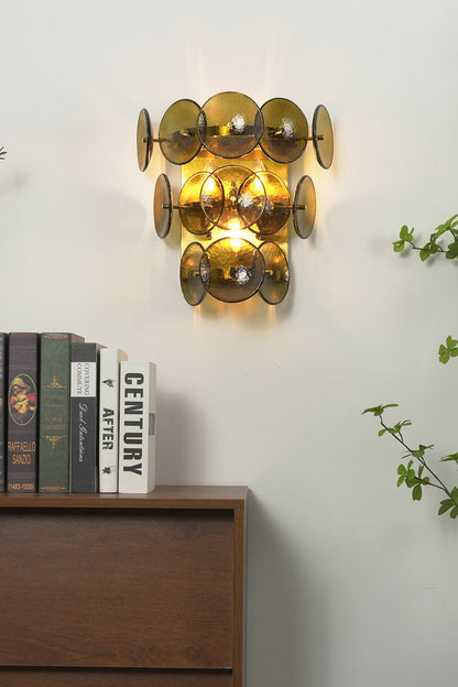 Lit olive green hammered glass wall lamp | Metal, Glass | Installed in a corner near a plant and books | vexa lamps