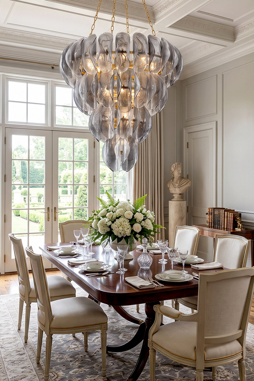 Ondine Cascading Leaf Glass Chandelier | Textured Smoked Glass and Gold Metal | Positioned over a classic wooden dining table surrounded by cream chairs near a window to the garden | vexa lamps