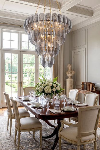 Ondine Cascading Leaf Glass Chandelier | Textured Smoked Glass and Gold Metal | Positioned over a classic wooden dining table surrounded by cream chairs near a window to the garden | vexa lamps