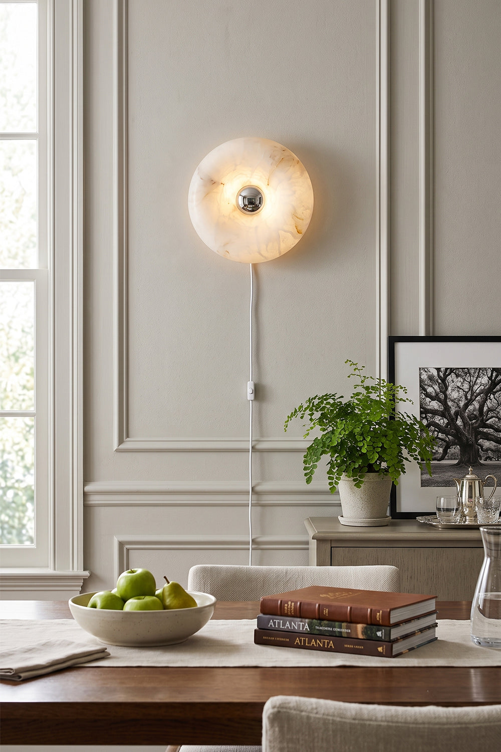 Ondine Ring Alabaster Wall Sconce illuminating a dining room with natural veining and a gold-toned wall plate.