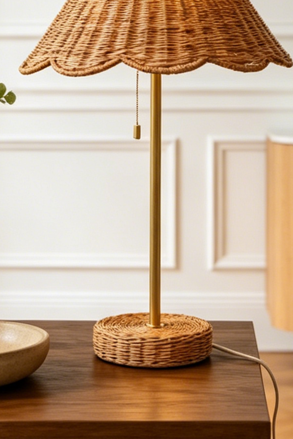 Osrilla Scalloped Rattan Table Lamp | Rattan, Brass | Close-up structural view focusing on the slim gold brass stem, classic pull-chain switch, and matching wrapped rattan base plate | Detail shot | vexa lamps
