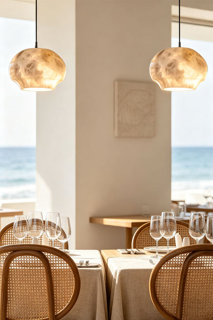 Ottilie Barrel Alabaster Pendant Light | Natural Alabaster and Metal | Pair of lights suspended in an oceanfront dining room with rattan chairs | vexa lamps