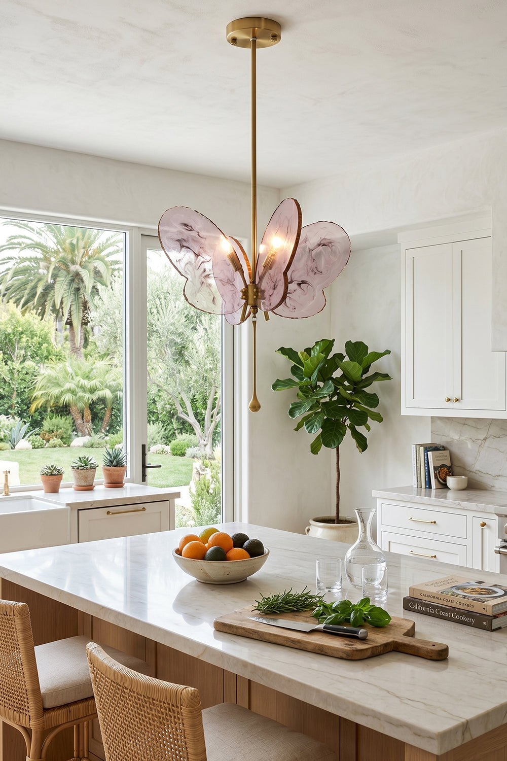 Papillon Glass Butterfly Pendant Lamp | Glass, Metal | Pink variant hanging over a white marble kitchen counter next to a large window showcasing garden views | vexa lamps