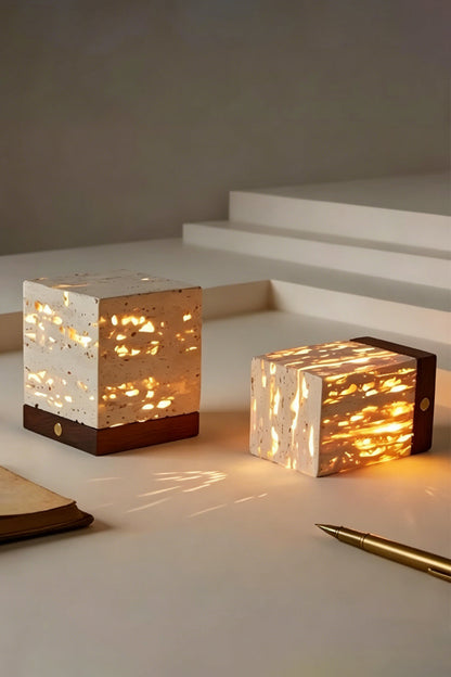 Radiant Monolith Travertine Table Lamp | Travertine, Wood | Pair of lamps on stepped platform | Lit and unlit variations shown | Intricate internal light patterns | vexa lamps