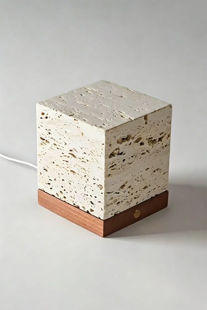Radiant Monolith Travertine Table Lamp | Travertine, Wood | Unlit angled view on grey surface | Porous stone voids detail | Dark wood base | vexa lamps