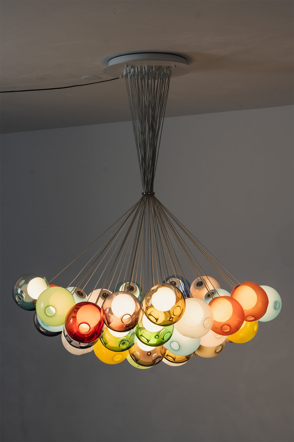 Rainbow Glass Bubble Cluster Chandelier | Glass, Metal | Side profile view of the wide crescent cluster arrangement fully illuminated against a neutral studio backdrop | vexa lamps