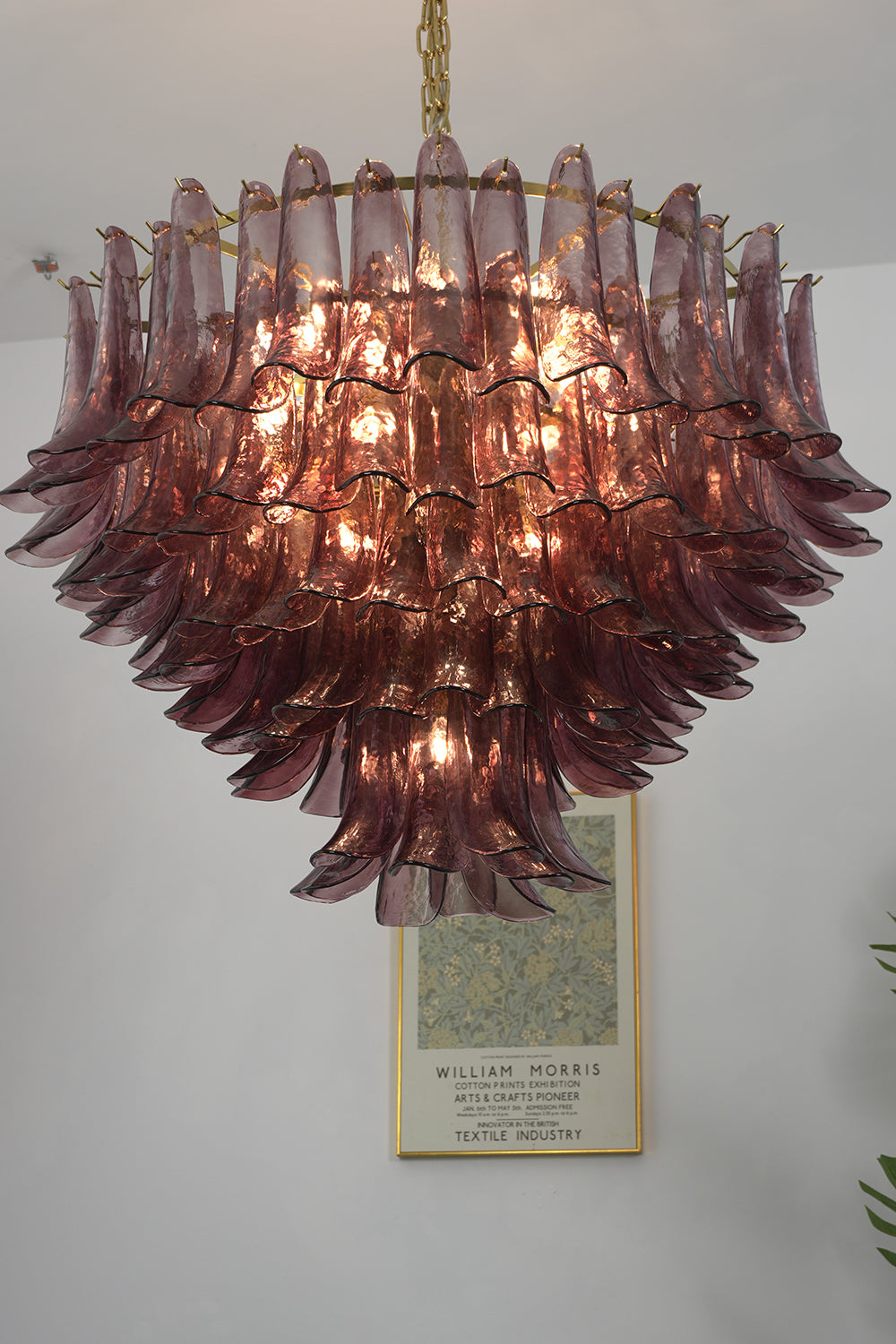 Regal Purple Cascade Chandelier | Glass, Metal | Front view of the lit chandelier against a plain wall, highlighting the warm glow | Detail shot | vexa lamps