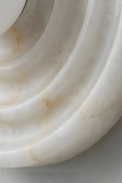 Rhea Rippled Alabaster Wall Sconce | Concentric Grooves Detail | Macro close-up view showing the sculptural layered depth of the circular rippled alabaster plate under soft lighting | Detail shot | vexa lamps