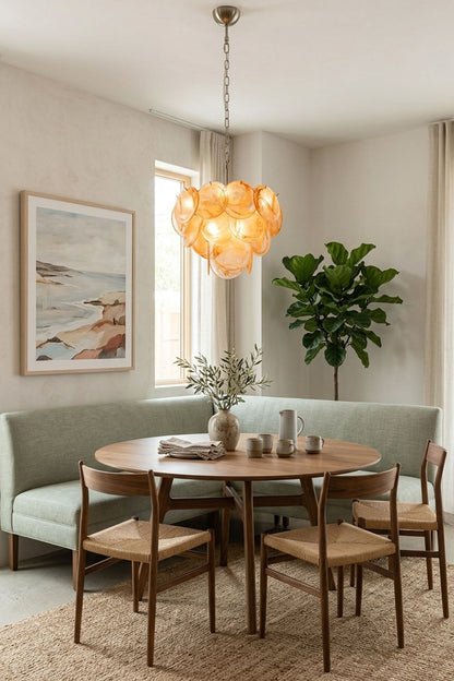 Romilly Layered Glass Disc Chandelier illuminating a modern dining area with a round table and green seating.