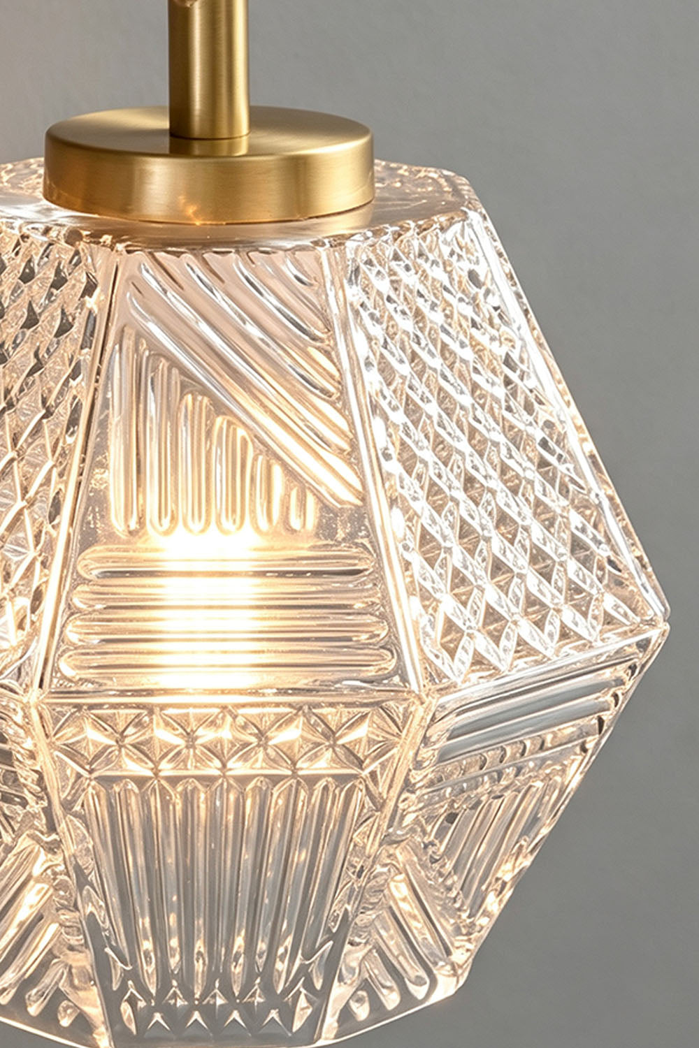 Rosamund Faceted Glass Wall Sconce | Faceted Glass and Brass | Close-up detail of the illuminated clear faceted glass shade | vexa lamps