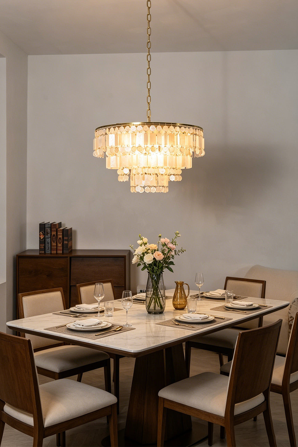 Elegant dining room featuring the Seraphina Capiz Cascade Metal Chandelier above a beautifully set table.