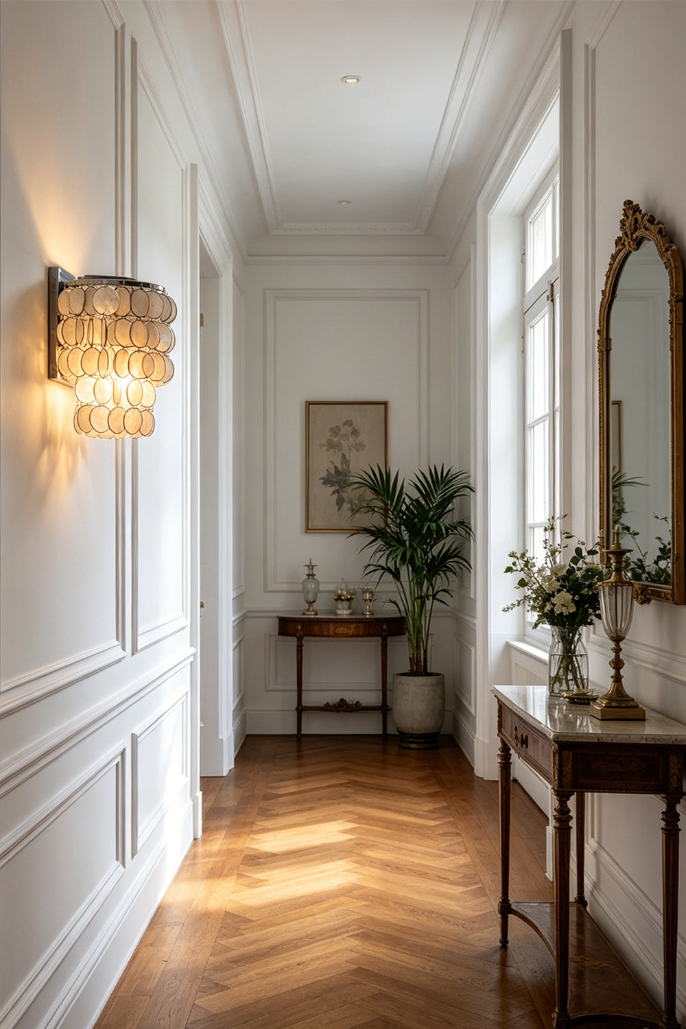 Shimmering Capiz shell wall sconce | Shell | Iron | Installed in a bright hallway with herringbone floors | vexa lamps