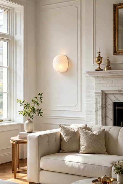 Silas Ribbed Glass Wall Sconce | Ribbed Glass, Metal | White frosted glass variant providing a soft ambient glow on a white paneled wall above a cream sofa in a living room | vexa lamps
