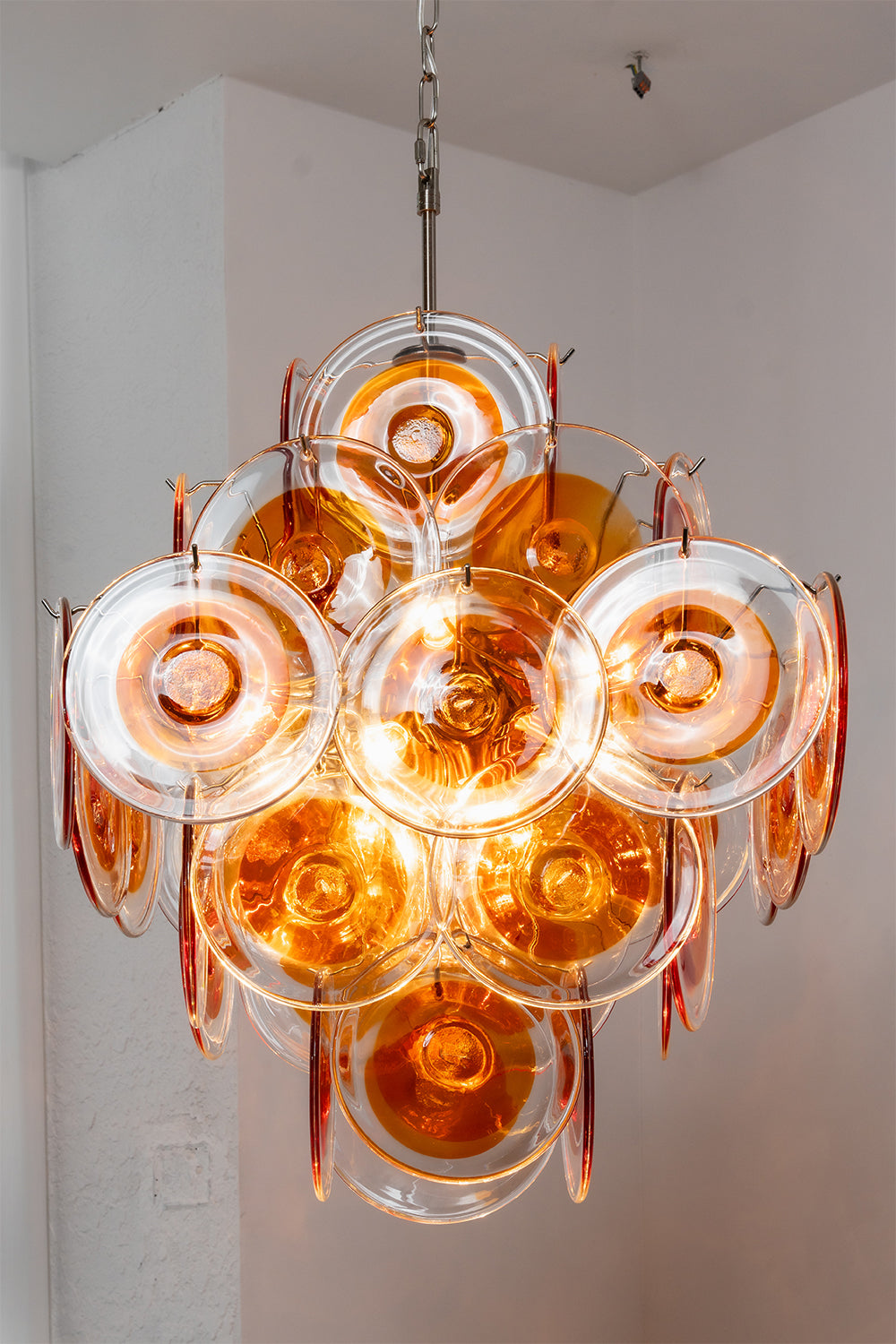 Lit amber glass chandelier showing warm glow | Metal, Glass | Warm ambient lighting effect in a clean space | vexa lamps