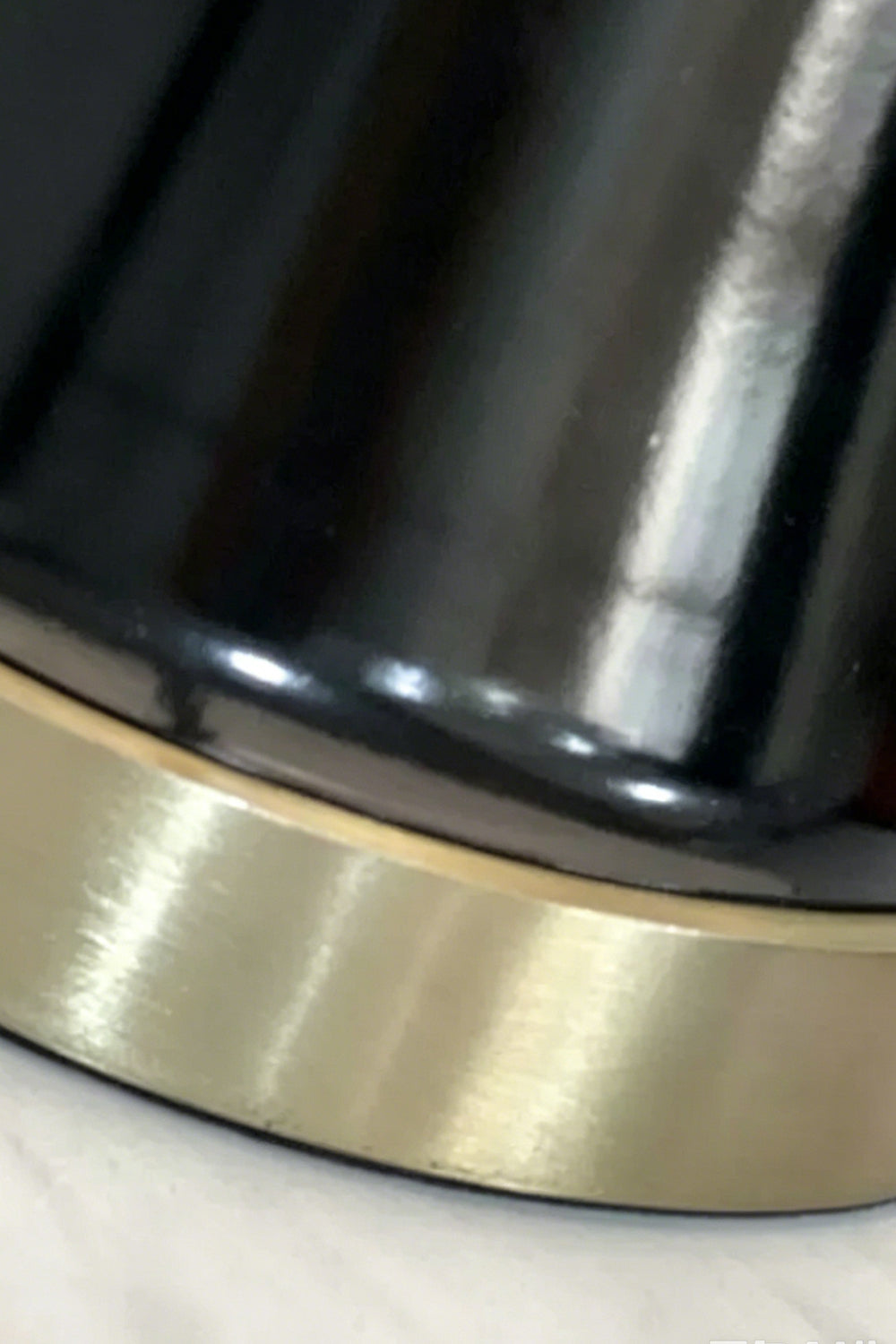 Close-up of the base of the Sovereign Alabaster Radiance Wall Lamp featuring a brass-plated ring and black lacquered column.