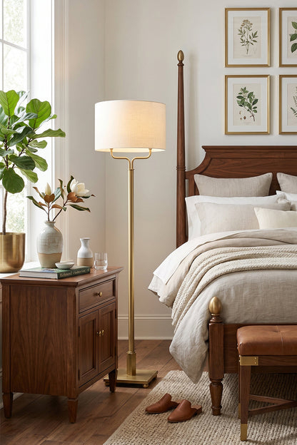 Sutton Modern Brass Floor Lamp beside a wooden bed and nightstand in a cozy bedroom setting.