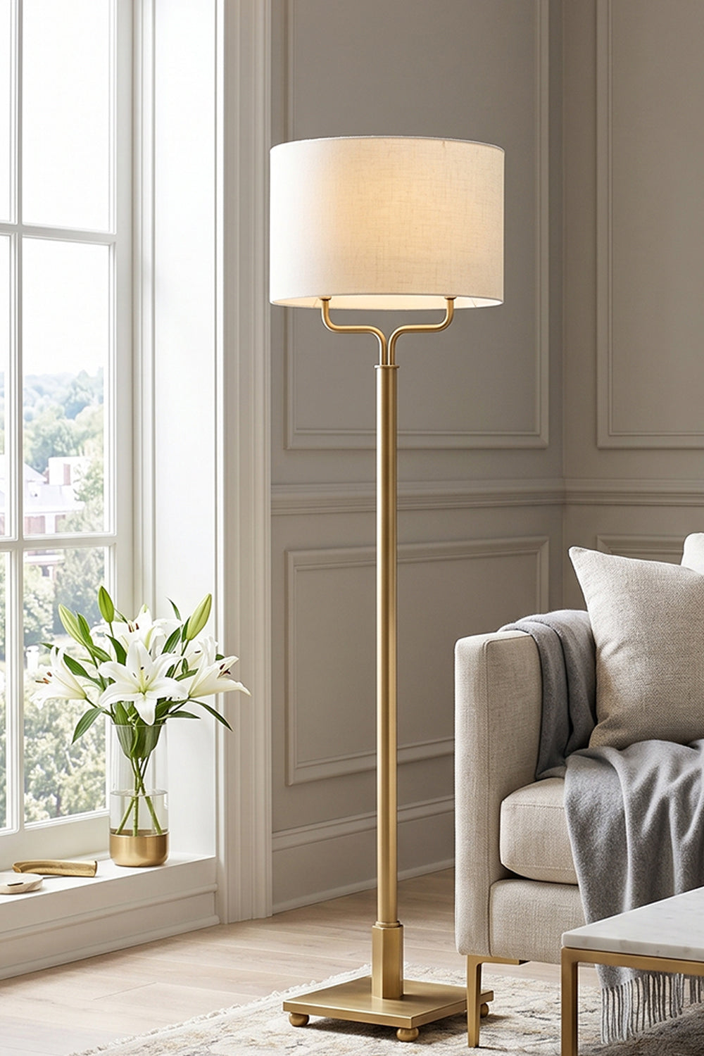 Sutton Modern Brass Floor Lamp with white linen drum shade in elegant living room setting.