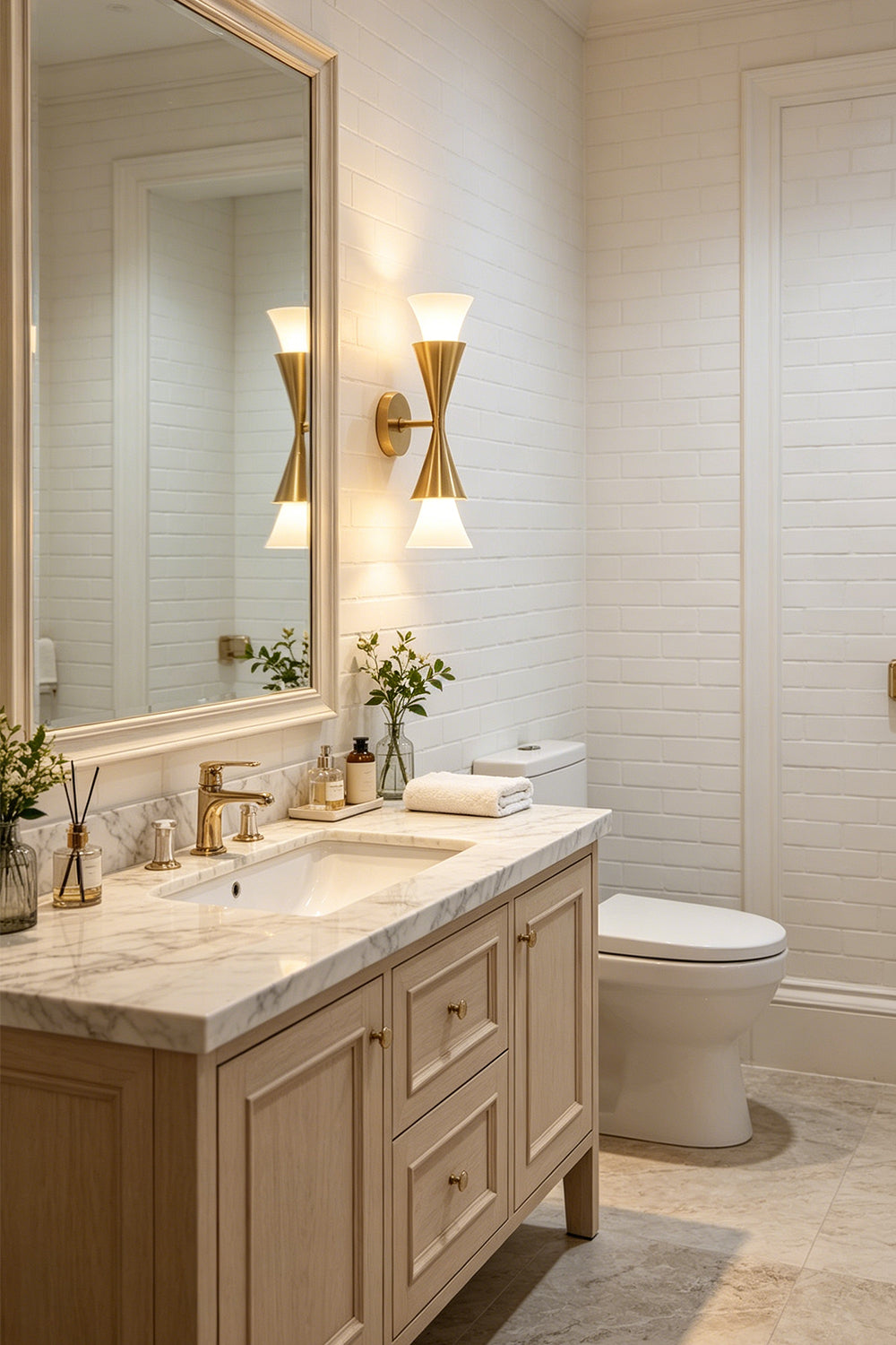 Sylvain Modern Torch Wall Sconce illuminating a stylish bathroom with light wood cabinets and elegant fixtures.