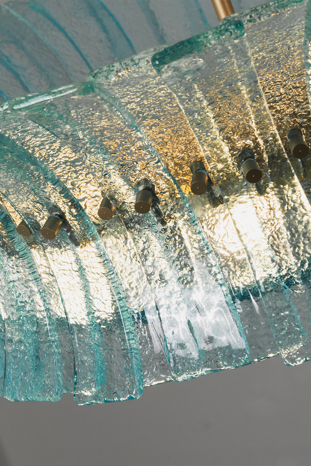 Thalassa Aquamarine Textured Glass Chandelier | Glass, Metal | Low angle shot looking up at the illuminated textured glass blocks diffusing a warm golden light through the blue-green panels | Detail shot | vexa lamps