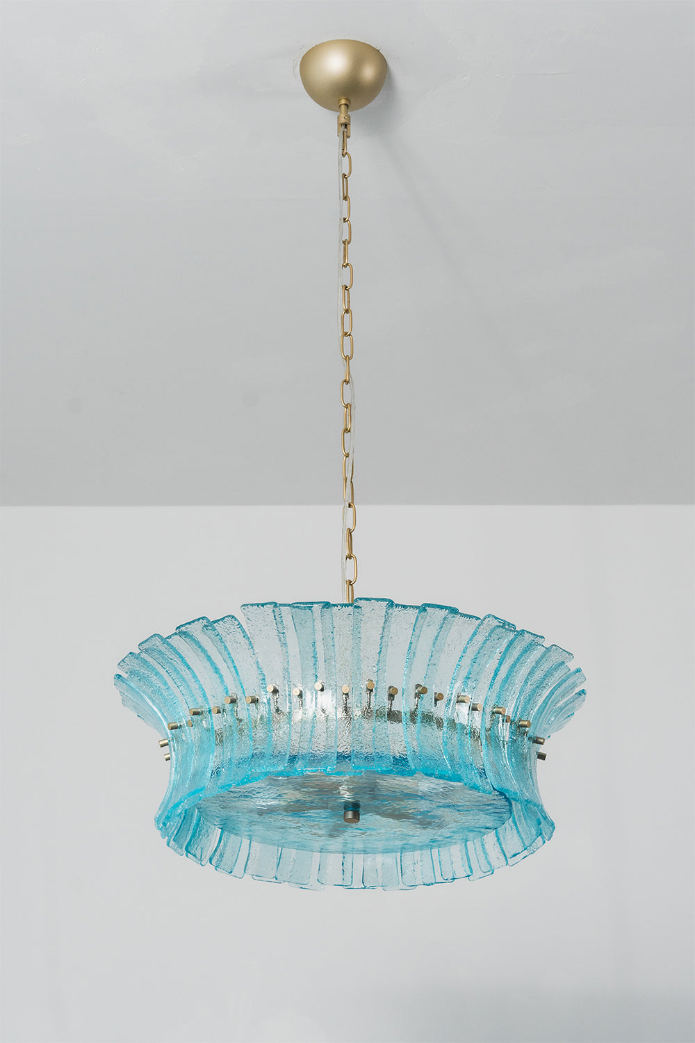 Thalassa Aquamarine Textured Glass Chandelier | Glass, Metal | Studio variant view of a shallower wide-rimmed tier version of the blue glass chandelier illuminated against a plain background | vexa lamps