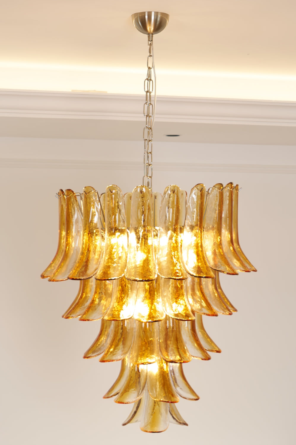 Lit Tiered Amber Lily Chandelier against plain ceiling | Metal, Glass | Side view showing warm illumination | vexa lamps