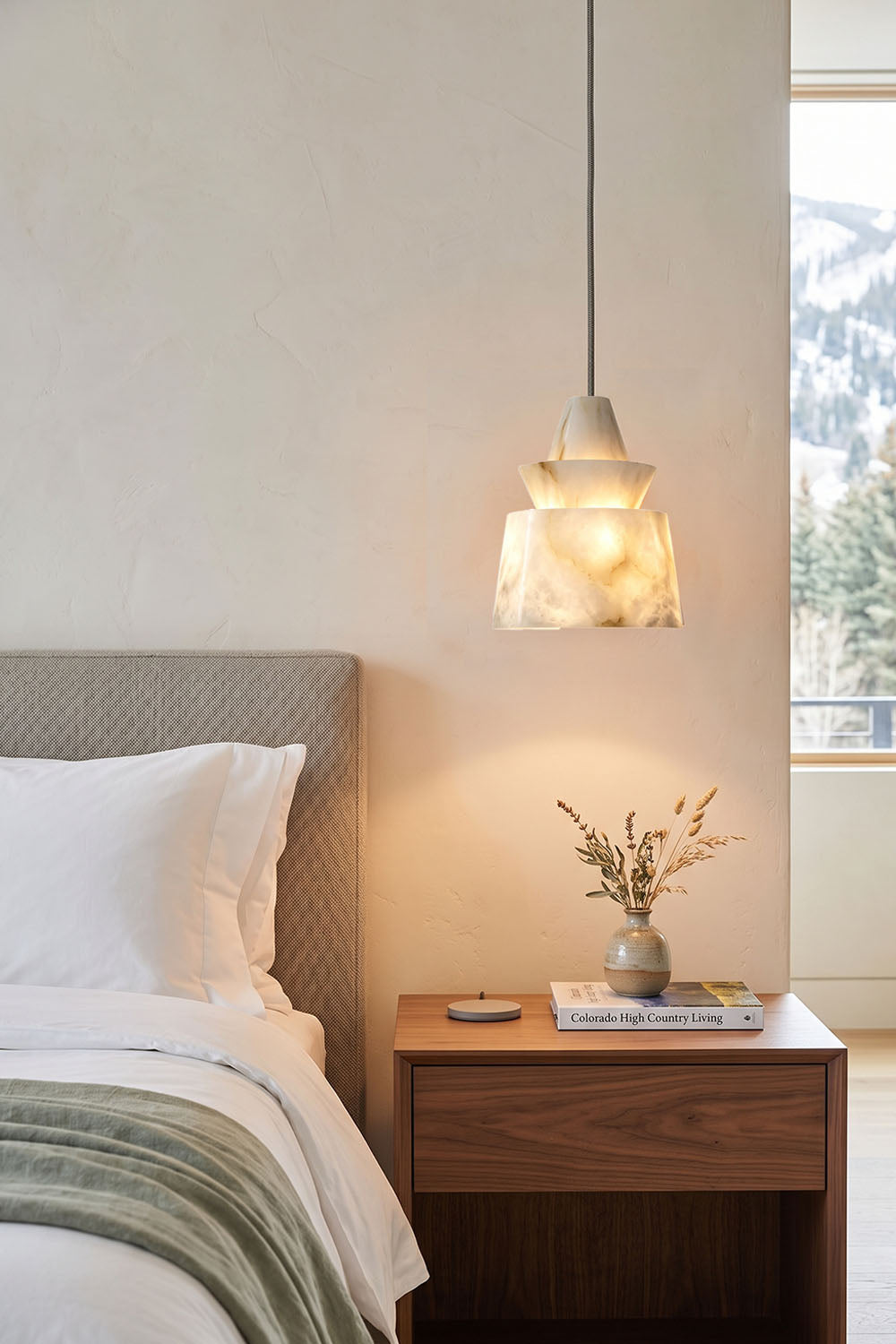 Tobiah Tiered Alabaster Pendant Light | Natural Alabaster and Metal | Hanging over a wooden nightstand beside a bed in a minimalist bedroom | vexa lamps
